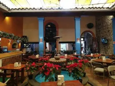 Patio de Café Lindo con columnas azules, fuente y nochebuenas